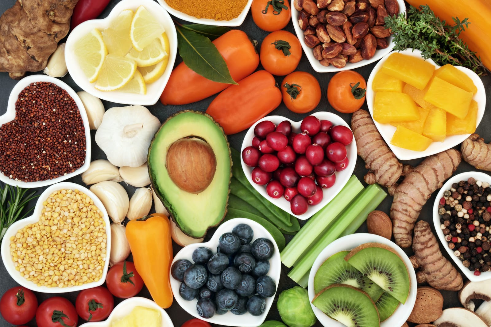 A variety of fruits and vegetables, some in or on heart-shaped plates. 