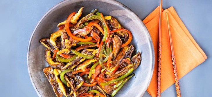 Bowl of shitake mushrooms and bell peppers with a napkin and chopsticks to the right.