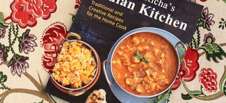 (Credit: One Sonic Bite) Copy of book sits on beige, floral tablecloth. The cover of the book is black and there is a bowl of curry pictured