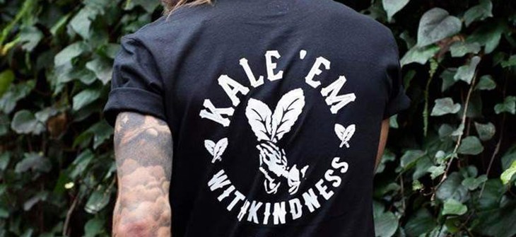 (Credit: Plant Faced) Man stands in front of ivy background wearing black t-shirt with white script that reads "Kale them with kindness"