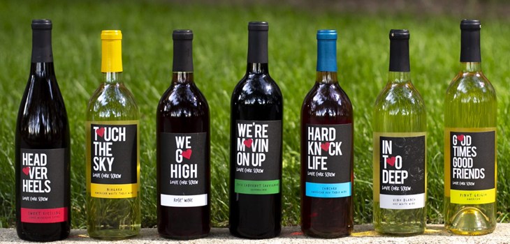 Bottles of wine lined up on a wall with a grassy background