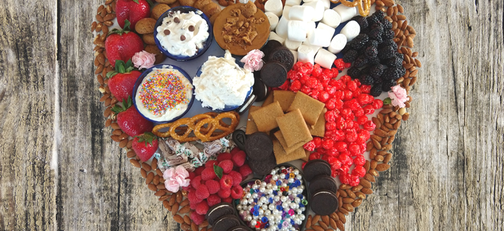 heart shaped dessert table with almons, oreos, kettle corn, berries and dips