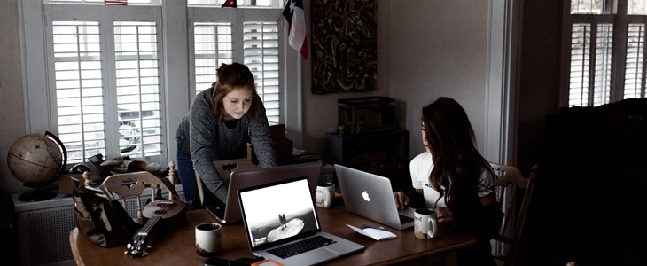 Women gathered around laptops in a dimly lit room