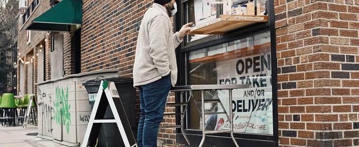 Man stands at a walk up window to but coffee at a local eatery