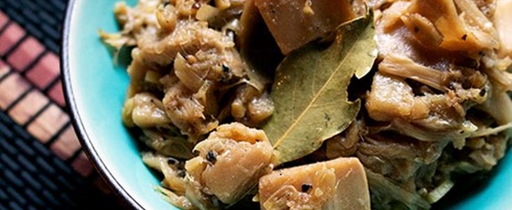 On a placemat in a bright blue bowl is the pulled jackfruit lechon with bay leaves