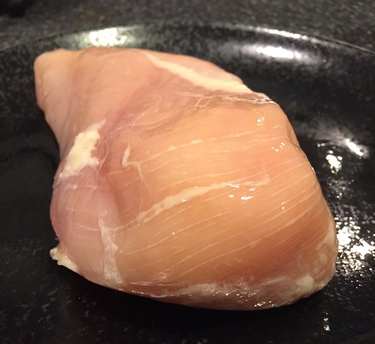A raw chicken breast with white striping