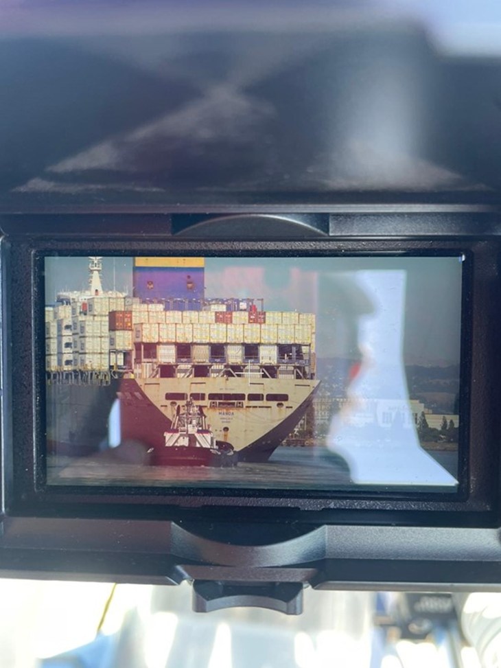 A viewfinder on a camera shows a ship carrying "cowtainers."