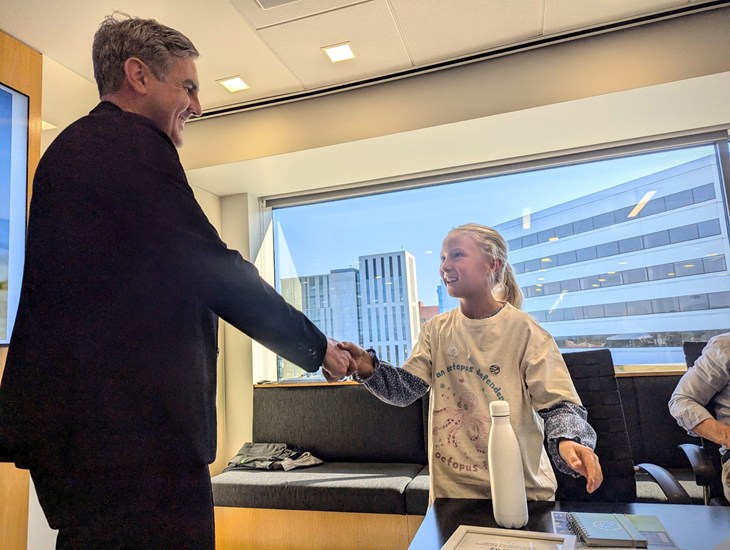 Lily Nierderhofer and Ben Williamson pose together in front of the front desk of the World Trade Center Portland in Oregon,
