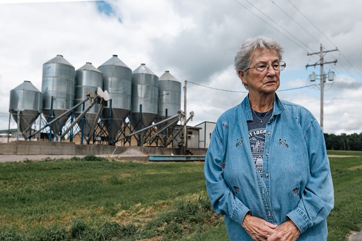 Virginia Drath stands in front of milk towers at a dairy factory farming.