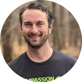 Cory Cerussi smiles while wearing a Compassion in World Farming t-shirt.